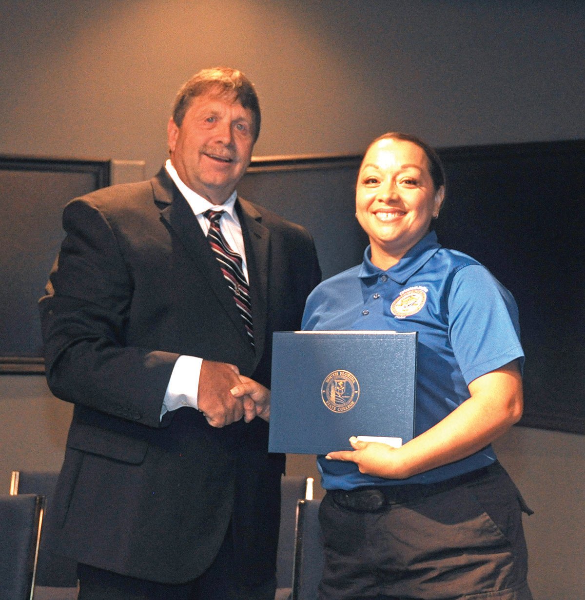 Joe Marble, coordinator, SFSC Criminal Justice Academy, presents Blanca Guereca, of Okeechobee, with her certificate.